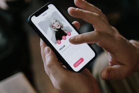 Close-up of hands using a dating app on a smartphone indoors. Modern technology and online dating.